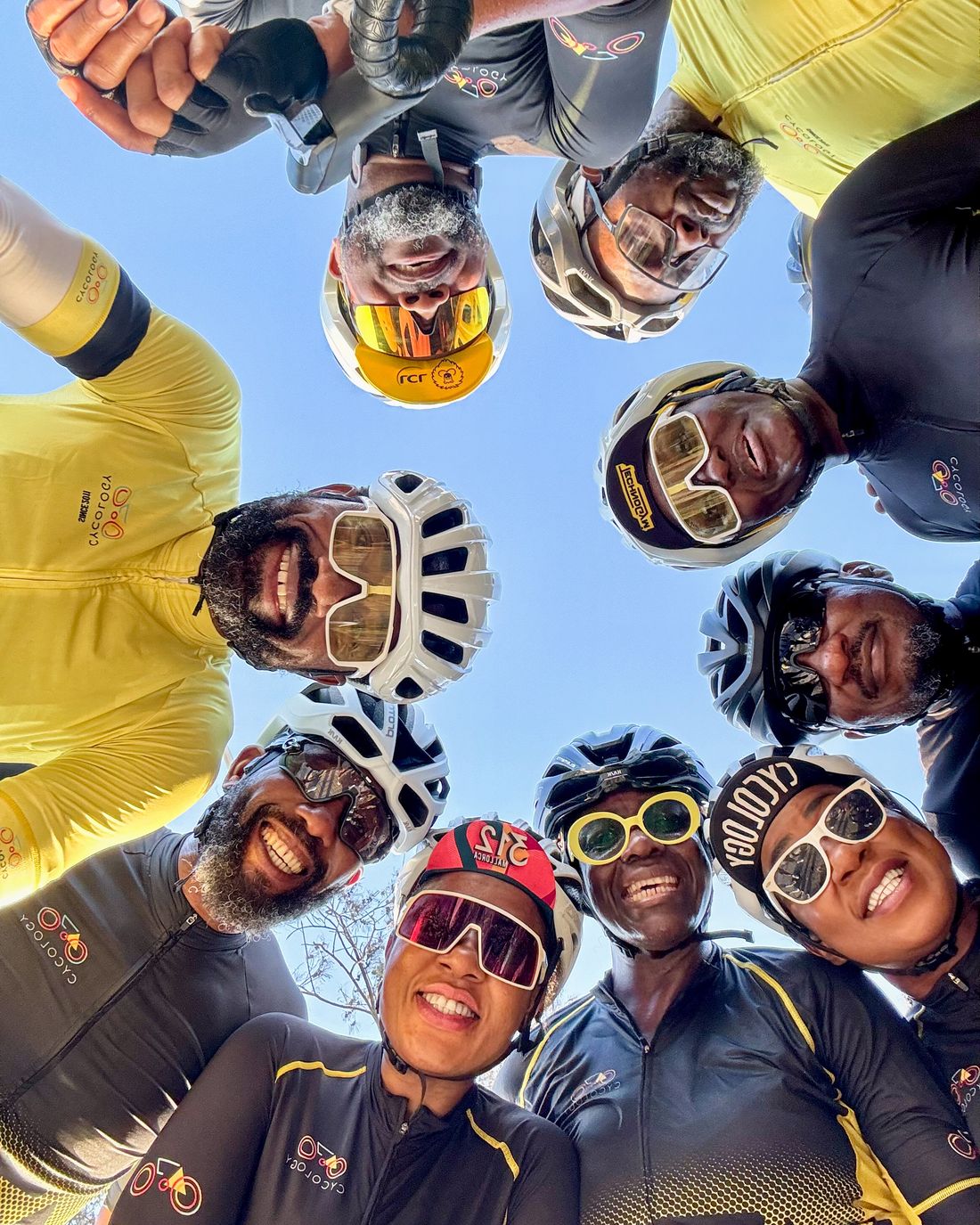 Cycology members in a circle huddle, looking down at the camera in club kit and helmets